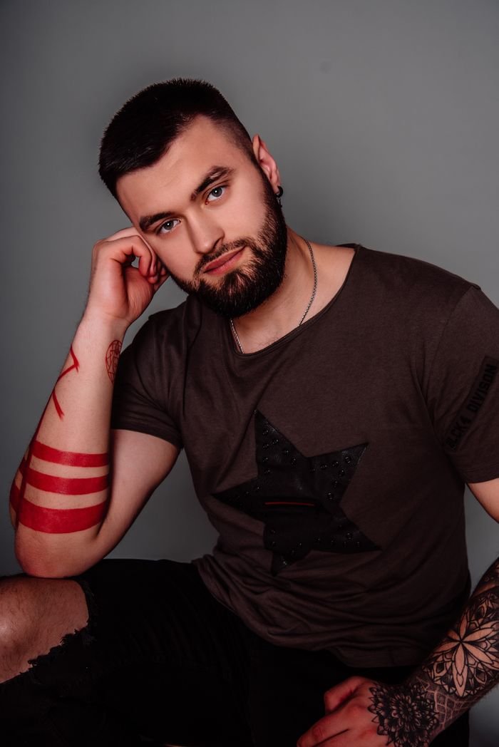 Portrait of a bearded man with tattoos in a studio setting, showcasing modern style.